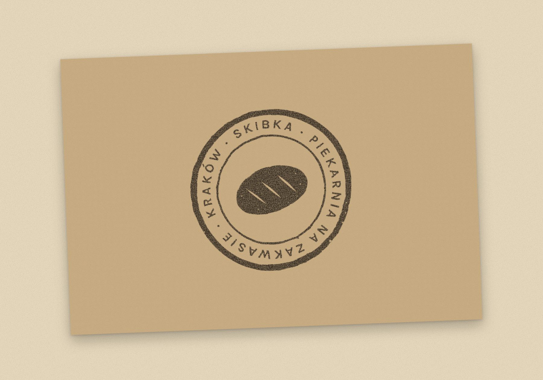 Awers wizytówki Skibki: brązowa pieczątka na papierze kraft.